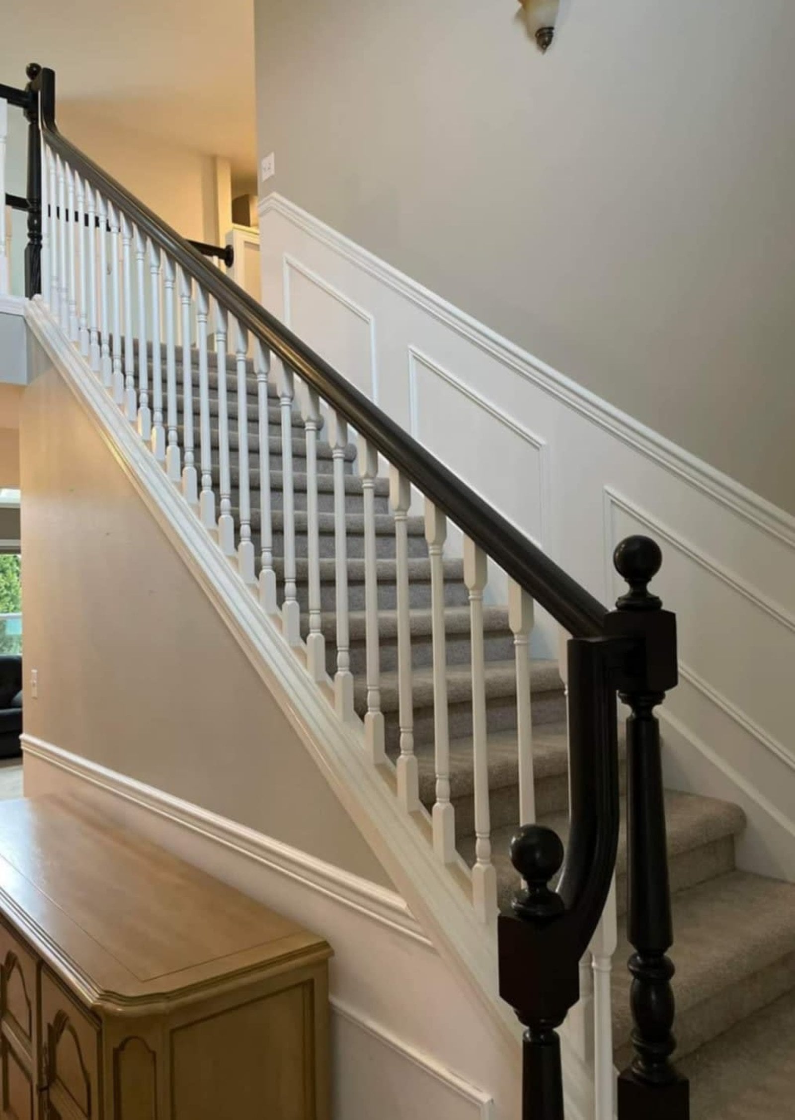 Interior staircase with two-tone painted railing in Snohomish County WA, featuring black newel posts and handrail with white balusters and wainscoting detail